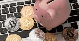 Cofrinho e moedas digitais sobre teclado, representando investimentos em criptomoedas.